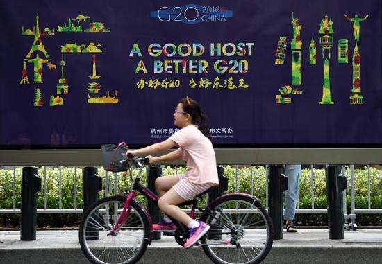 8月27日，在杭州市西湖南山路，一個(gè)小朋友騎車從G20宣傳畫前經(jīng)過(guò)。 新華社記者 鞠煥宗 攝.jpg