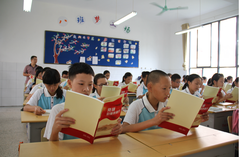 學(xué)生們集體學(xué)習(xí)《黨旗引領(lǐng)我前行》一書。.png